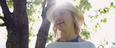 güzel genç esmer kız güneşli parkta sabun köpüğü esiyor.