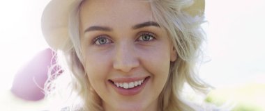 Poz ve güneşli yaz gündüz dışarıda gülümseyen güzel genç kadın