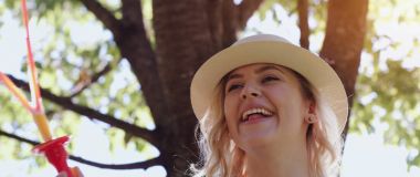 güzel genç esmer kız güneşli parkta sabun köpüğü esiyor.