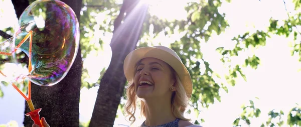 太陽に照らされた公園でシャボン玉を吹かゴージャスな若いブルネットの少女 — ストック写真