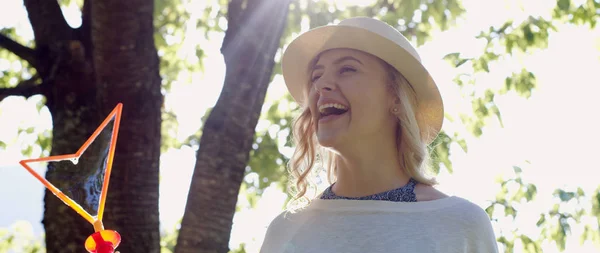 太陽に照らされた公園でシャボン玉を吹くゴージャスな若いブルネットの少女 — ストック写真