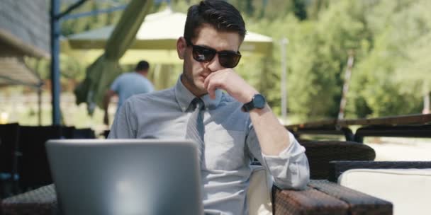 Junger Gutaussehender Geschäftsmann Mit Sonnenbrille Und Laptop Outdoor Café — Stockvideo