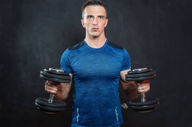 siyah arka plan üzerine dumbbells ile egzersiz genç kaslı adam