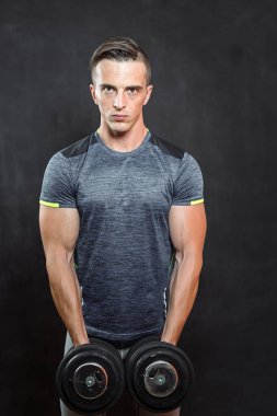 siyah arka plan üzerine dumbbells ile egzersiz genç kaslı adam