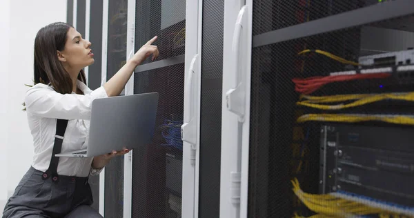 Technician performing maintenance tasks in a server room rack