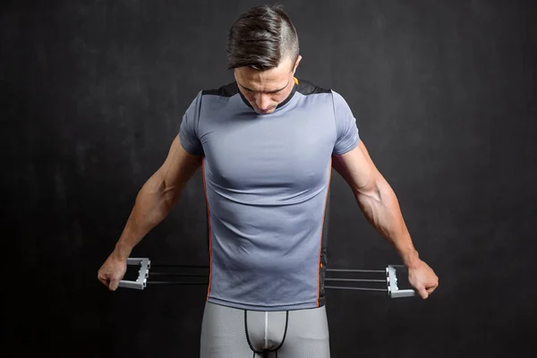 Fitness man exercising with stretching band in studio.