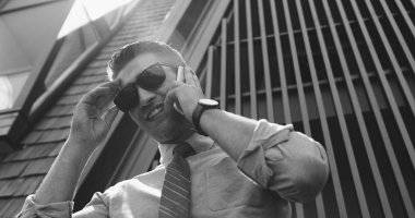 Ofis dışında cep telefonu ile iş adamı. Ofis onun arkasında Binası çelik satırlarından