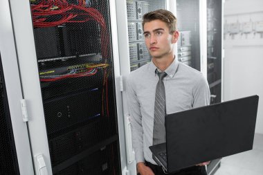 Bir adamın Portriat endişelendim, veri merkezi içinde laptop sorun çözmeye çalışan. 
