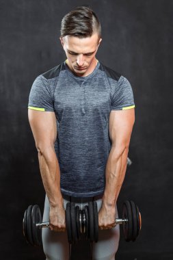 siyah arka plan üzerine dumbbells ile egzersiz genç kaslı adam