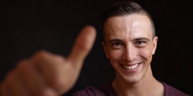 Kameraya gülümseyen genç adam. Siyah arka plan. Açık yüz