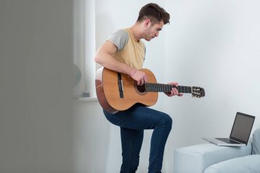 Yakışıklı genç oyuncu evde bir gitar çalmak. Entertaiment zaman