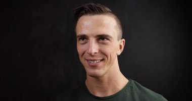 Siyah arka plan üzerinde gülümseyen yakışıklı genç bir adam portresi