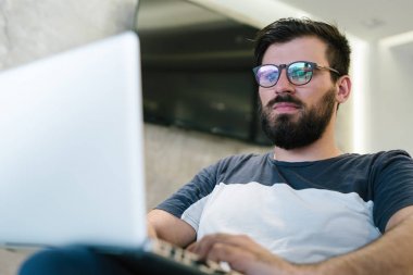 Gözlük takan ve diz üstü oturma ve tipik sakallı bir işadamı yakın çekim.
