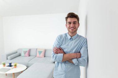 Mavi gömleğin içinde poz ve gülümseyen genç işadamı