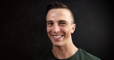 Siyah arka plan üzerinde gülümseyen yakışıklı genç bir adam portresi