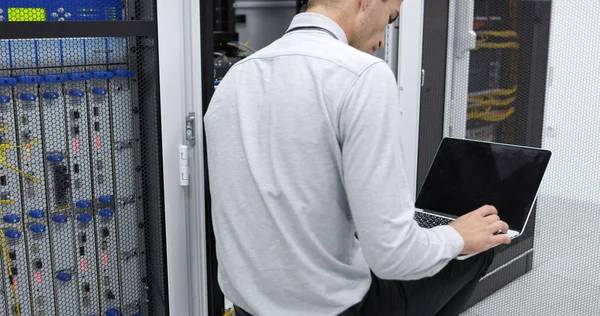 Technician performing maintenance tasks in a server room rack