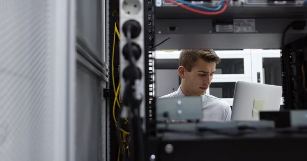 Technician performing maintenance tasks in a server room rack