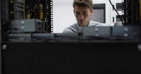 Technician performing maintenance tasks in a server room rack