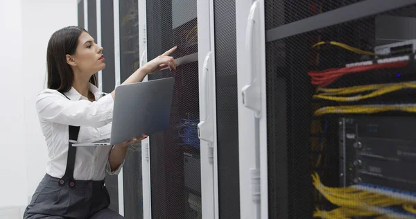 Technician performing maintenance tasks in a server room rack