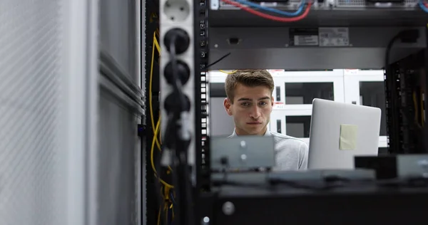 Technician performing maintenance tasks in a server room rack