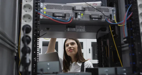 Technician performing maintenance tasks in a server room rack