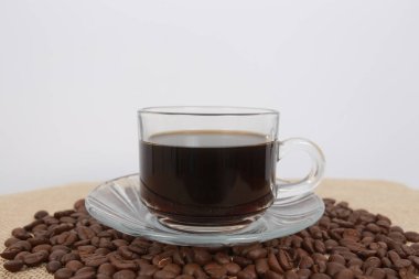 Kahve ve donut beyaz bir masada siyah kahve çekirdekleri