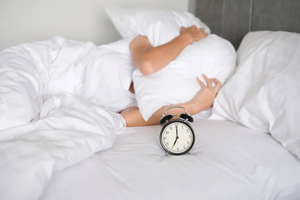 Yatakta uyuyan bir kadın çalar saati kapatır ve sabah uyanır, seçici bir şekilde odaklanır.