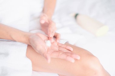 Asyalı kadın, kremi ellerine ve vücuduna sür. Güzellik konsepti..