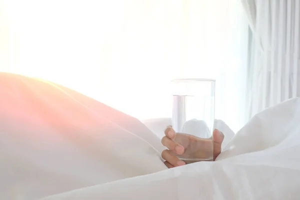 Kadın yatağın üzerinde güneş ışığıyla cam tutuyor..