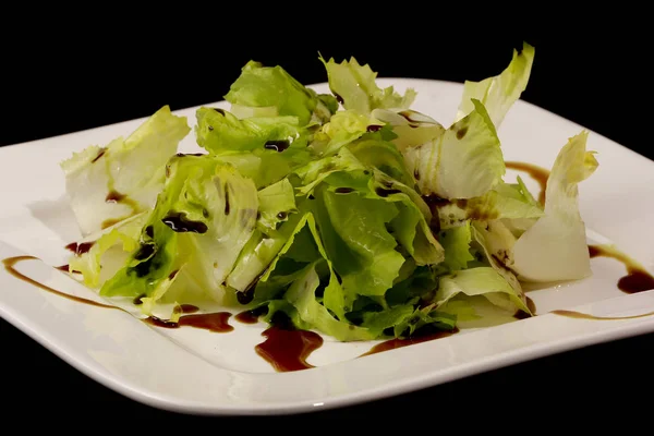 Salad with pumpkin oil on a black background — Stock Photo, Image