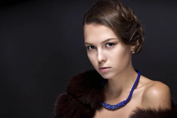 Portrait of a teenage girl in a fur coat on a dark gray backgrou — Stock Photo, Image