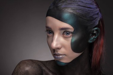 Gri bir arka plan üzerinde yaratıcı makyajlı bir kadın portresi. 