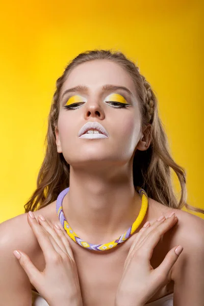 Retrato de una joven con maquillaje creativo sobre una espalda amarilla — Foto de Stock
