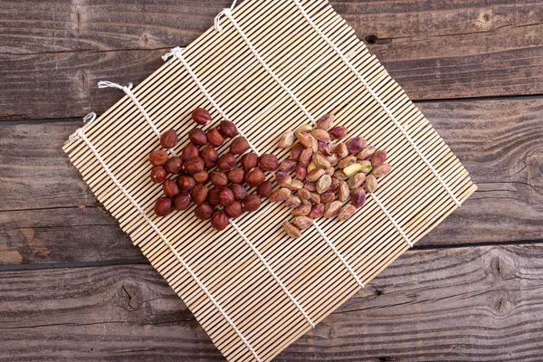 Foto de pistachos pelados de concha y avellanas tumbados en un m — Foto de Stock