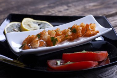 Gri tahtada siyah tabakta kızarmış karidesler..