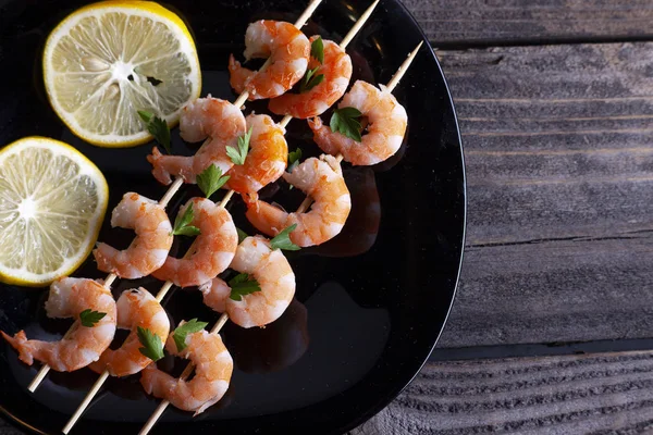 Boiled shrimp in a black plate on gray boards. — Stock Photo, Image