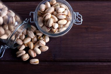 Ahşap arka planda cam kavanozlarda fıstıklar.