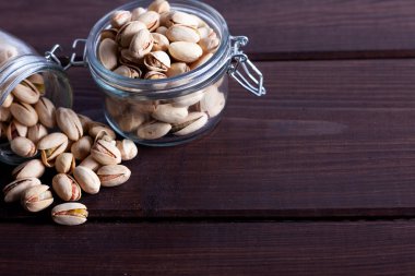 Ahşap arka planda cam kavanozlarda fıstıklar