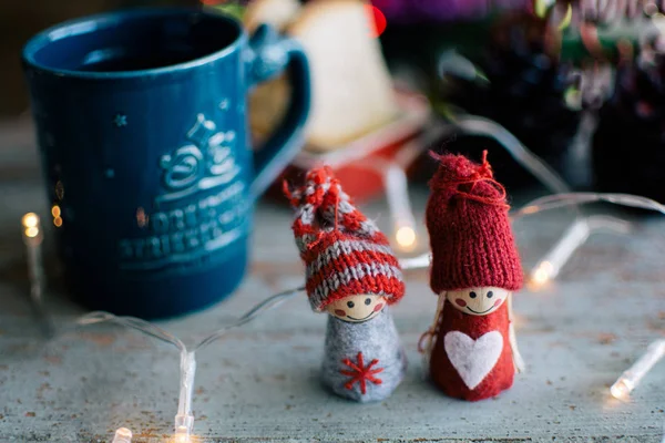 Two knitted dolls and a cup of coffee with christmas background — Stock Photo, Image