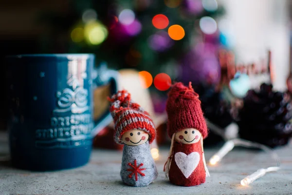 Two knitted dolls and a cup of coffee with christmas background — Stock Photo, Image