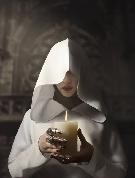 女巫在白色蒙面斗篷持有燃烧蜡烛站在城堡 — 图库照片