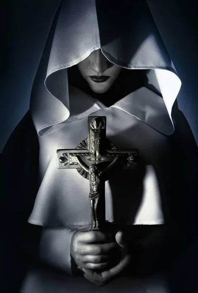 Bir çapraz holding beyaz kukuletalı pelerin dua eden kadın.