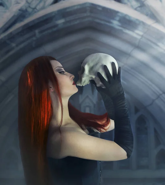 Genç ve güzel Gotik kadın Kızıl saçlı siyah korse ve holding ve kalenin bir insan kafatası ayakta öpüşme eldiven.