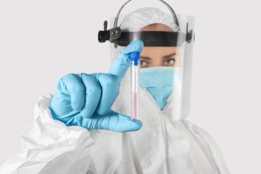 Tecrit edilmiş genç kadın bilim adamı ya da laboratuvar çalışanı bir test tüpünü aşı ya da reaksiyonla tutuyor ve gösteriyor. Sağlık, tıbbi ve pandemik koronavirüs konsepti.