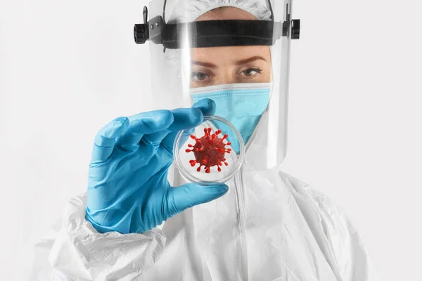 Tecrit edilmiş genç bir kadın bilim adamı ya da laboratuvar çalışanı elinde bir petri kabı ve covid-19 molekülü tutuyor. covid-19, sağlık, bilim ve tıp kavramı.
