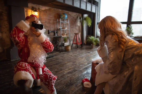 Święty Mikołaj robi zdjęcia i jest w pobliżu choinki i blondynki Snow Maiden — Zdjęcie stockowe