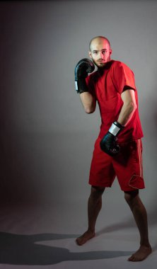 Duvarın arka planında kırmızı bandajlı kas dövüşçüsü kickbox 'ı.