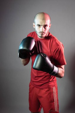 Boksör, kırmızı şortlu siyah eldivenli kırmızı tişörtlü boks maçına hazırlanıyor.