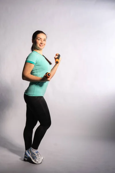 Chica fitness es con mancuernas y deportes en la camisa azul sobre fondo blanco — Foto de Stock