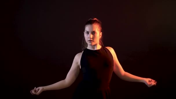 Girl on a black background dancing and stroking the thigh and snaps his hand — Stock Video